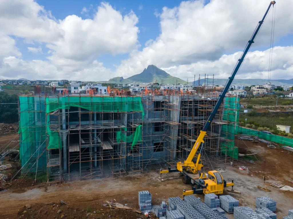 A mobile crane working alongside an Anna City block under construction, with the mountains behind